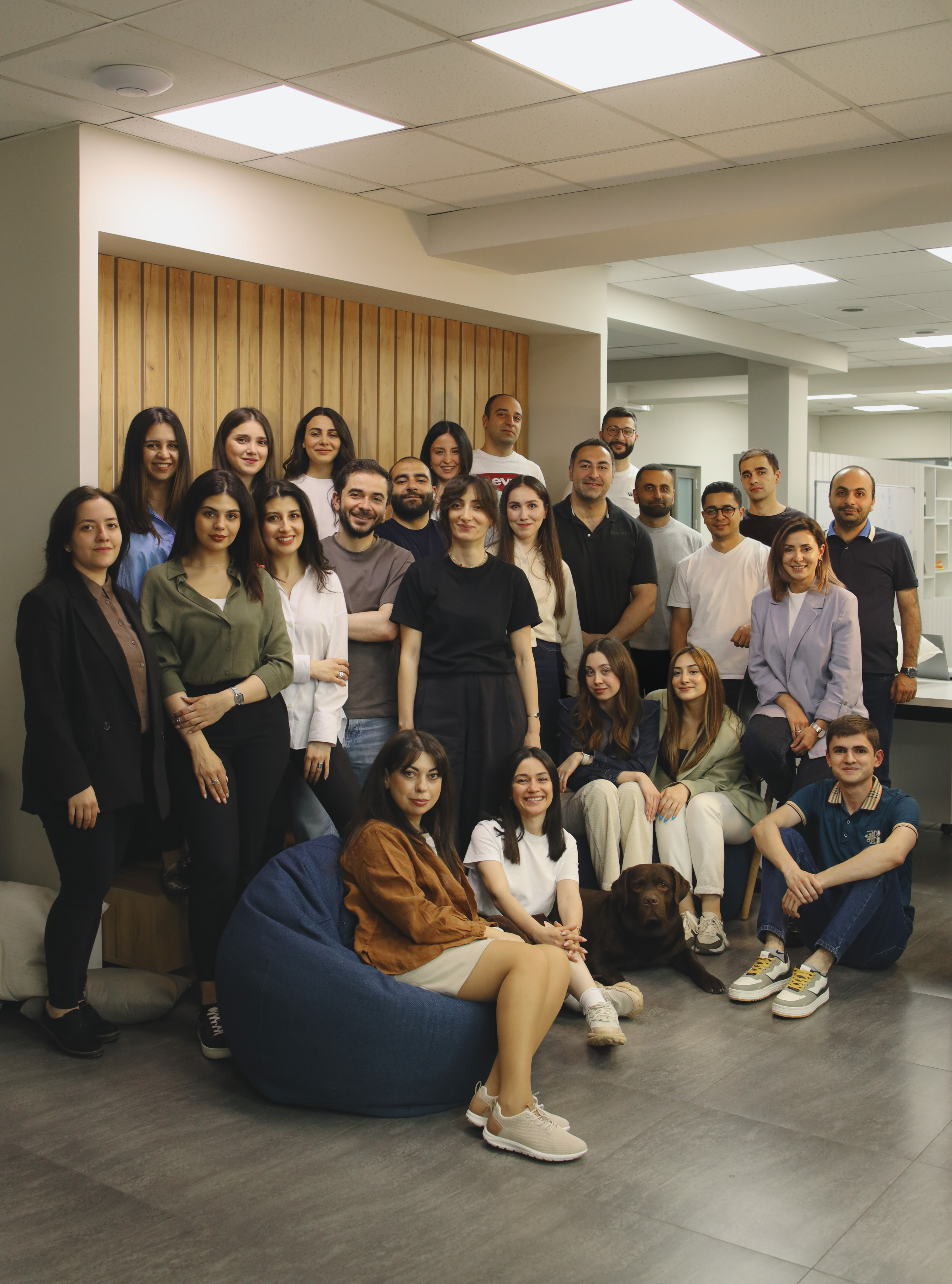 A large, diverse team of about 15 people posing together for a group picture in a common area.