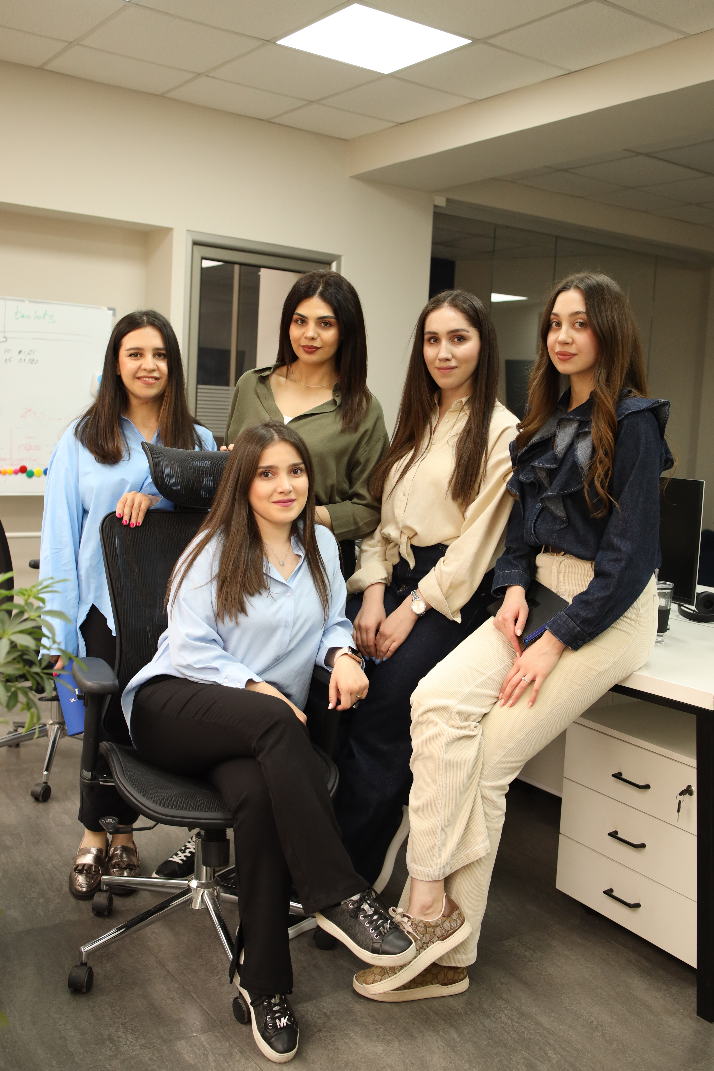 A large, diverse team of about 15 people posing together for a group picture in a common area.